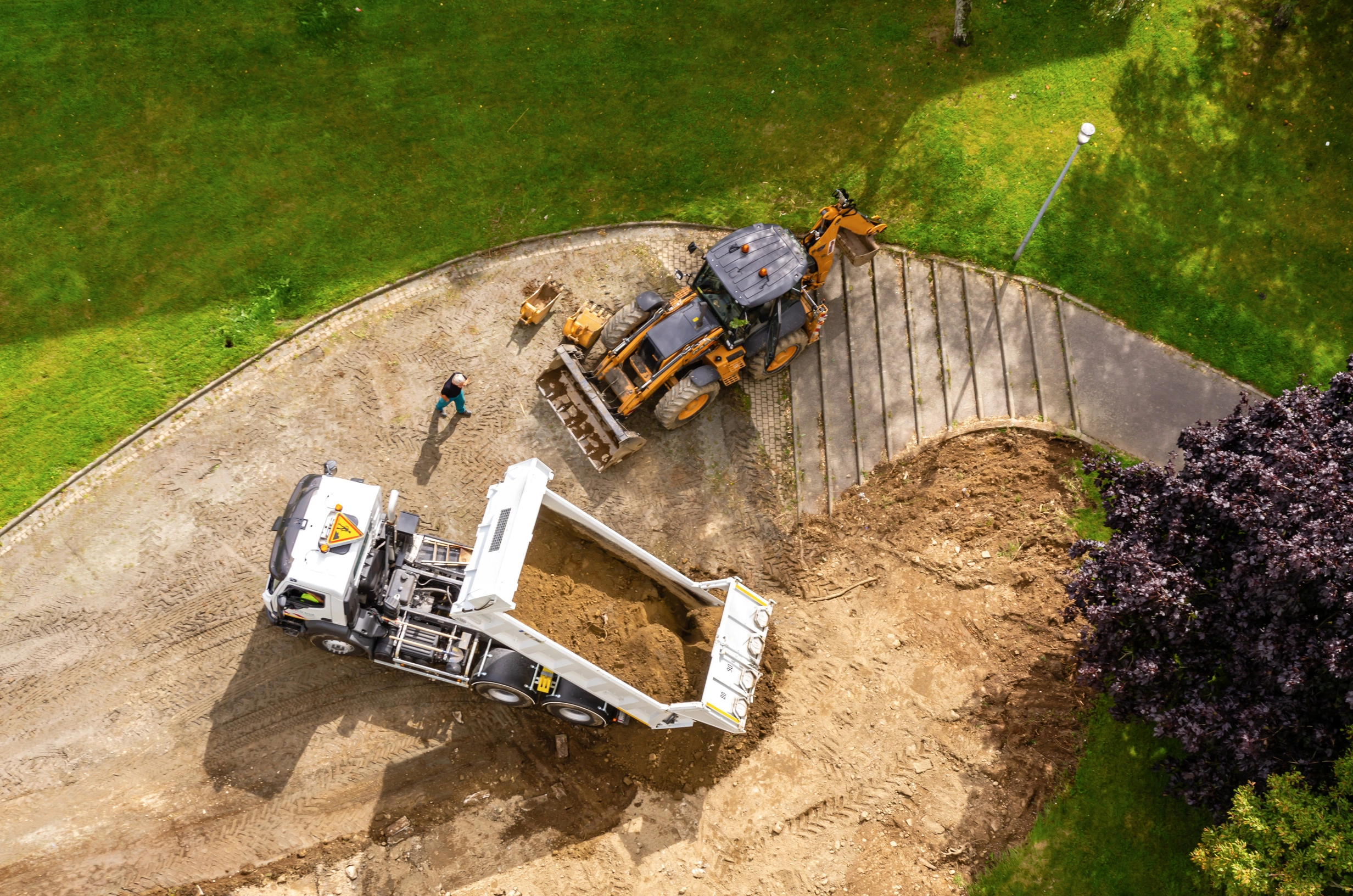 Camion et tractopelle en action sur un chantier de terrassement dans un jardin