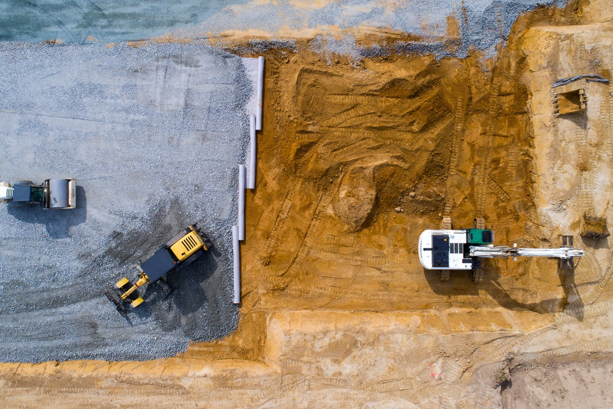 Vue aérienne d'un chantier de terrassement avec divers engins, illustrant les travaux de nivellement et de préparation du sol pour la construction