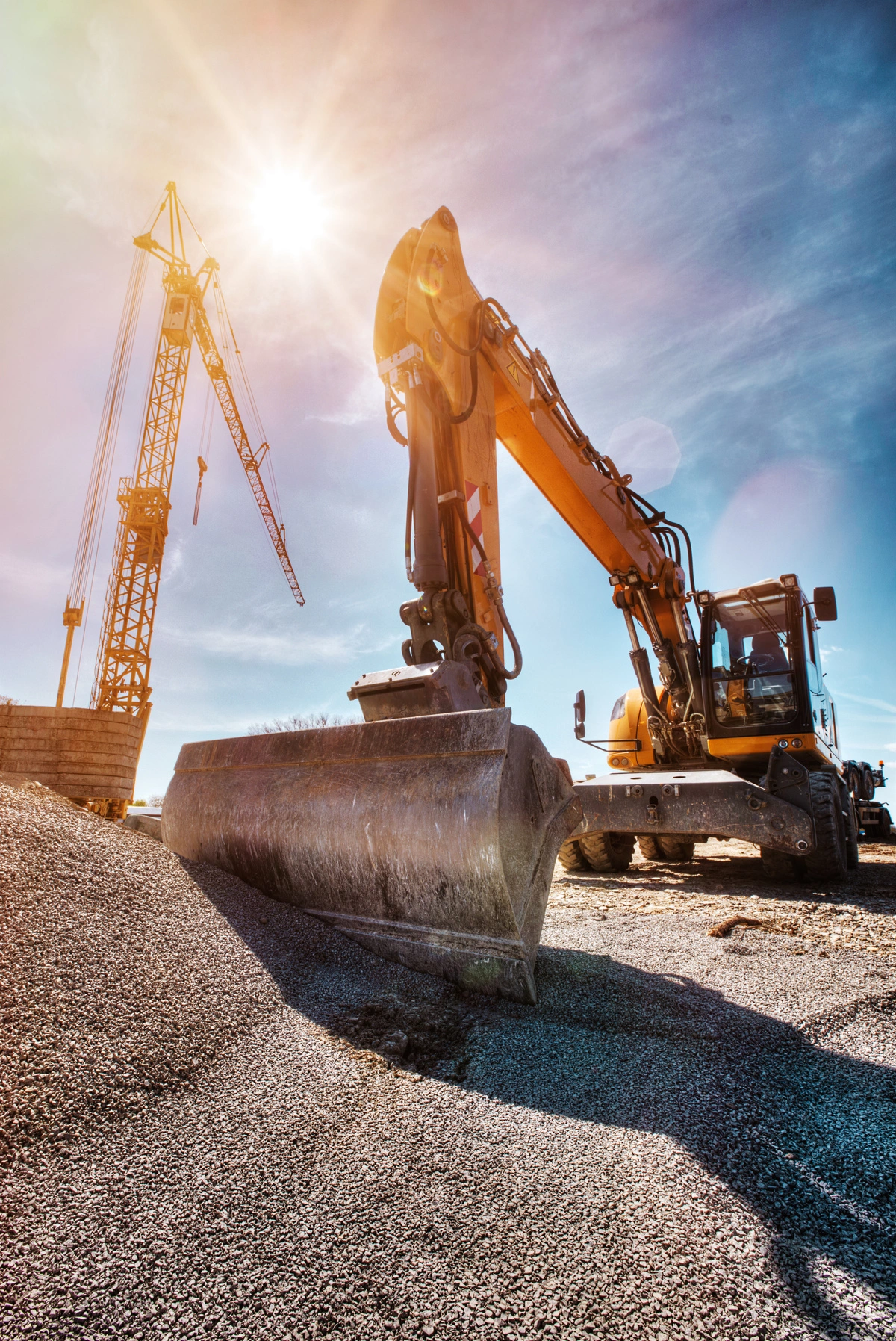 Pelleteuse travaillant sur un chantier de terrassement sous un ciel ensoleillé, illustrant l'utilisation d'engins lourds pour la préparation du terrain