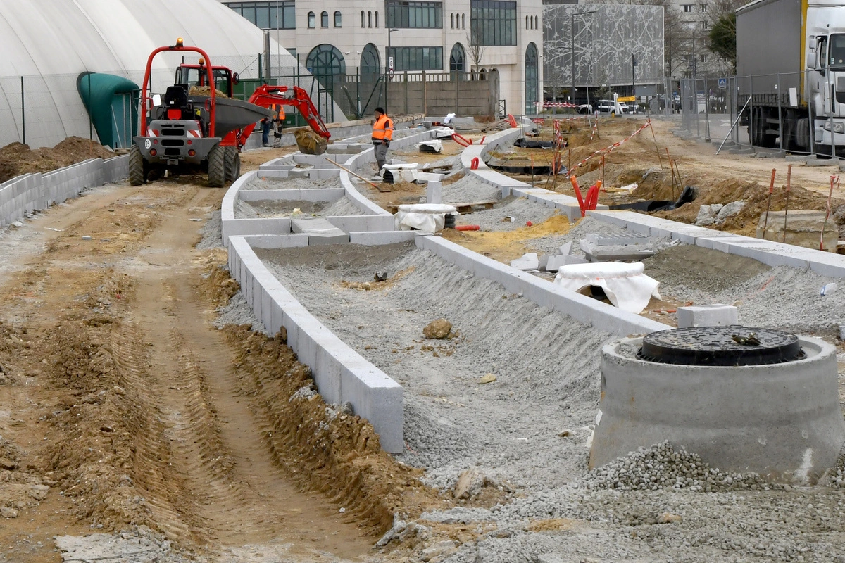 Engins de chantier et ouvriers travaillant sur un projet d'aménagement urbain, montrant les étapes de préparation et de pose de bordures